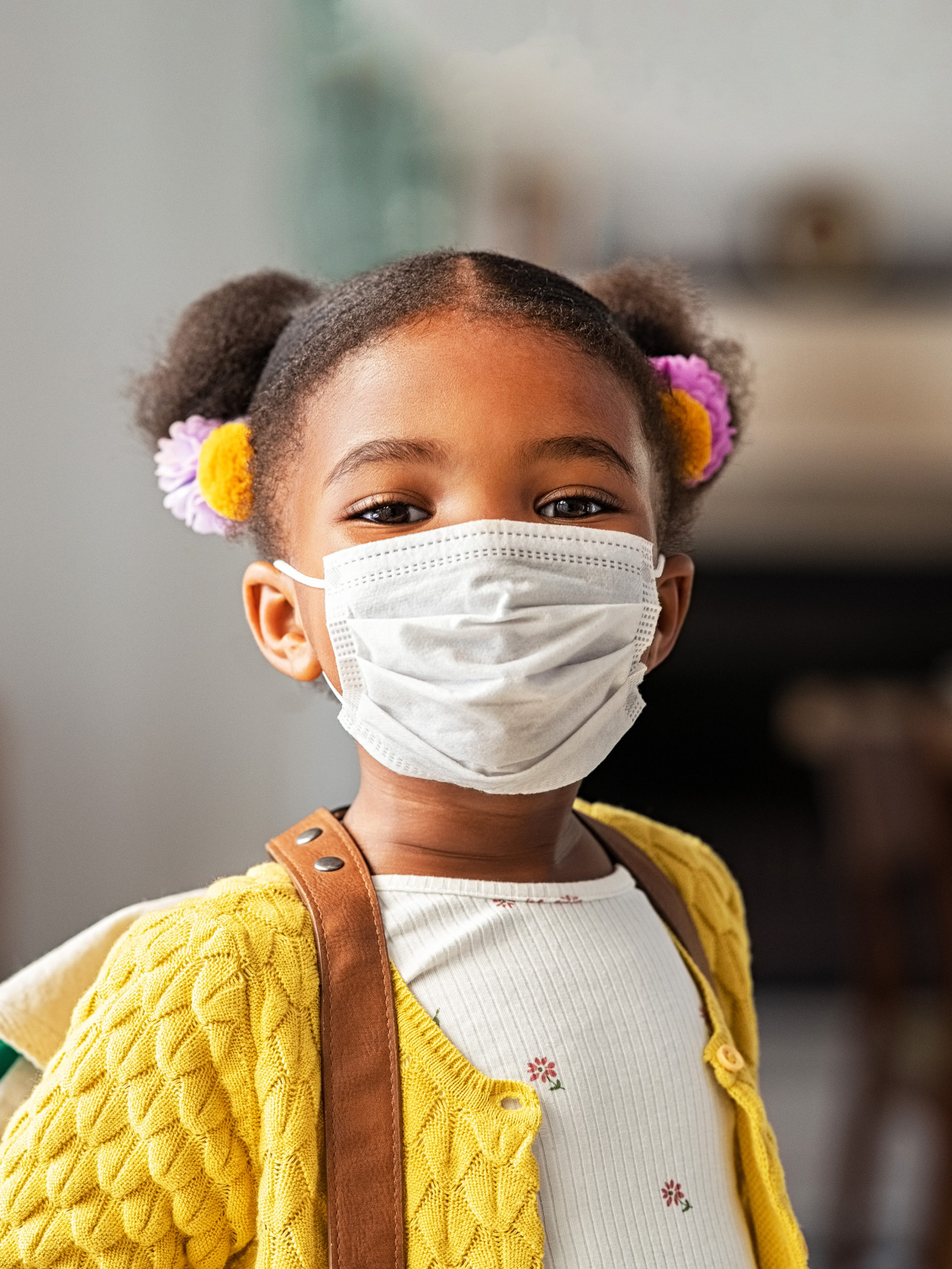Little girls smiles with backpack on and mask